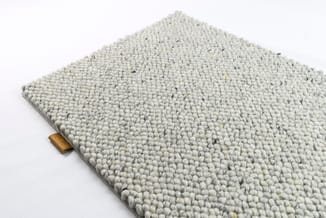 Grijsbeige tapijttegel met bolletjestextuur en houten label, tegen witte achtergrond.