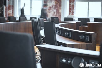Moderne vergaderkamer met U-vormige tafel in donker hout, grijze stoelen en ingebouwde technologie, grote ramen op achtergron
