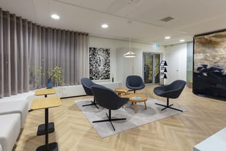 Moderne kantoorruimte met zwarte ergonomische stoelen, houten bijzettafels, grijze gordijnen, houten vloer en abstracte wandk