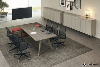 Moderne vergaderruimte met houten tafel, zwarte bureaukstoelen, grijze kasten, rood accent, display en raam.