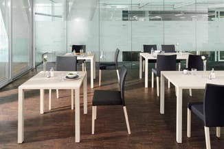 Kantoorruimte met witte rechthoekige vergadertafels, zwarte stoelen, glazen wanden en houten vloer.
