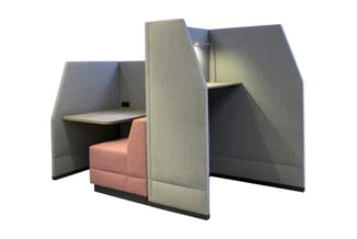 Gesloten werkplek met grijze geluidsabsorberende wanden, roze zitmeubel, werkblad en bovenkasten met verlichting.