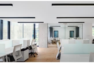 Modern open kantoor met witte werkplekken, houten vloer, zwarte systeemplafond-elementen, glazen scheidingswanden en ergonomi