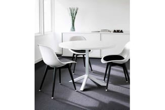 Moderne vergadertafel in wit met driepoot onderstel, omgeven door drie witte stoelen met zwarte poten in een lichte kantoorru