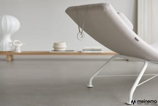 Witte ergonomische bureaustoel met hoofdsteun in minimalistisch kantoor, op grijze vloer naast houten bureau.