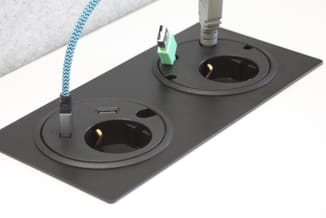 Zwart bureau-stekkerdoos met twee stopcontacten, USB-poort en groene aardingsclip, blauwe gevlochten stroomkabel.