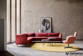 Modern interieur met rode hoekbank, roze fauteuil, gele ovale vloerkleed, twee bijzettafels en abstract wanddoek op beige muu