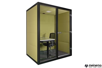 Akoestische belcel met gele wanden, zwarte aluminium frame, glazen deur en raam, voorzien van werkplek met bureau, bureaustoe