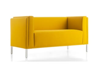 Gele designbank met hoge zijwanden en metalen poten, vrijstaand tegen witte achtergrond.