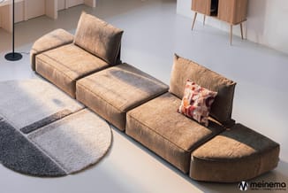 Modulaire loungebank in beige/taupe ribfluweel, uitgestrekt in L-vorm met chaise longue, geplaatst in showroom met grijze tap