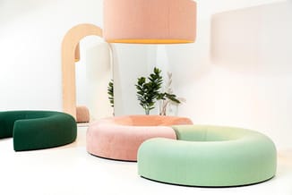Ronde loungebanken in groen, roze en beige in minimalistische ruimte met houten lamp en decoratieve planten.