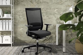 Zwarte ergonomische bureaustoel met netrug en zitting in modern kantoor met betonnen muur, witte kasten en potplant.