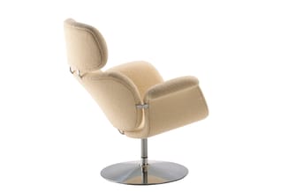 Beige fauteuil met hoge gebogen rug, zitting en armleuningen, op zilverkleurig voetwerk met ronde basis.