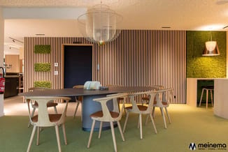 Moderne vergaderzaal met ovale tafel in grijs, lichte houten stoelen, verticale houten wandpanelen, groene moswanden, hanglam