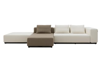 Modulaire bank in beige en taupe stof met chaise longue, losse kussens en zwart onderstel tegen witte achtergrond.