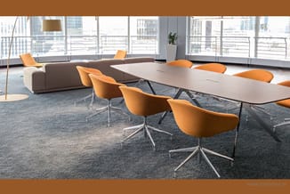 Moderne kantoorruimte met grijze vergadertafel, oranje draaistoelen met aluminium onderstel, bruine hoekbank en grote raampar
