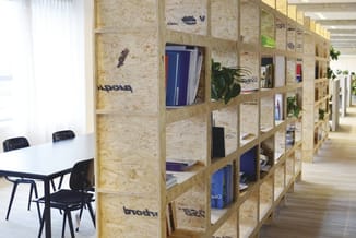 Modern kantoorinterieur met houten kastensysteem uit kurk/hout met open vakken, planten, boeken en kantoorbenodigdheden. Zwar