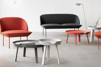 Moderne kantoormeubelen: rood stoelen en zwarte bank met grijze tafels in minimalistische setting.