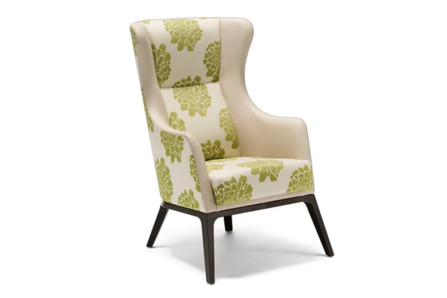 Fauteuil met hoge rugleuning, creme kleurig bekleding met groen bladmotief, zwarte houten poten.