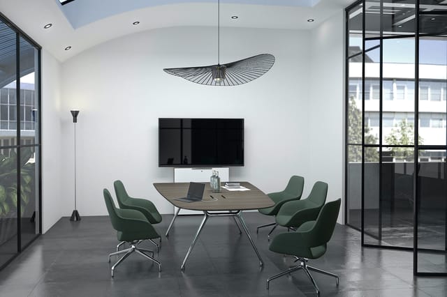 Moderne vergaderruimte met ovale tafel, vier groene stoelen, wandmontage TV, hangende design lamp en raampartijen met zicht o