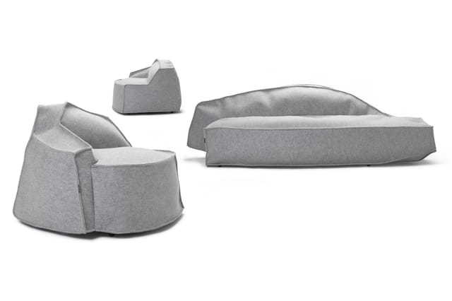 Drie grijze zitmeubels: twee ronde fauteuils en één langwerpige loungebank, alle in grijs stofmateriaal.