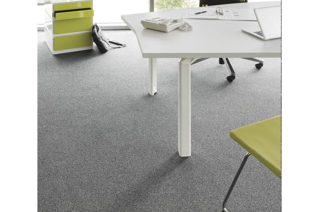 Modern kantoor met witte rechthoekige tafel, grijze tapijtvloer, lime groene kastjes en zwarte bureaustoel bij raam.