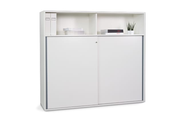 Witte kastenwand met bovenkasten en twee schuifdeuren, gevuld met ordners, dozen en plantje.