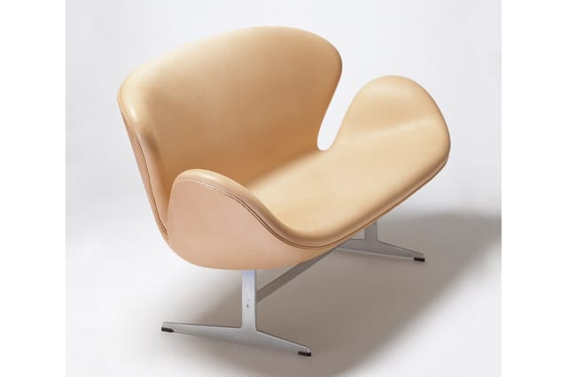 Beige leren loungestoel met organische vorm en zilveren metalen onderstel op lichte achtergrond.