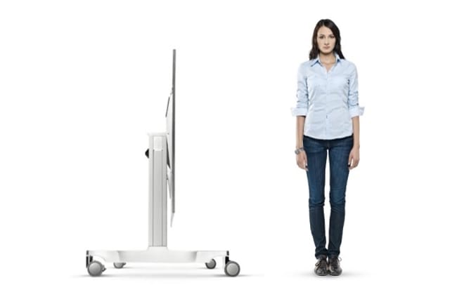 Wit mobiel display-standaard naast vrouw in lichtblauw shirt en donkerblauwe jeans voor maatverwijzing.
