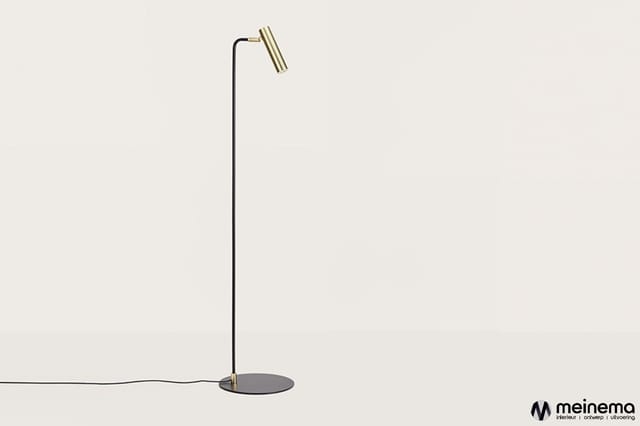 Staande leeslamp met zwart metalen staander, ronde zwarte voetplaat en geborsteld messing lampenkop tegen neutrale achtergron