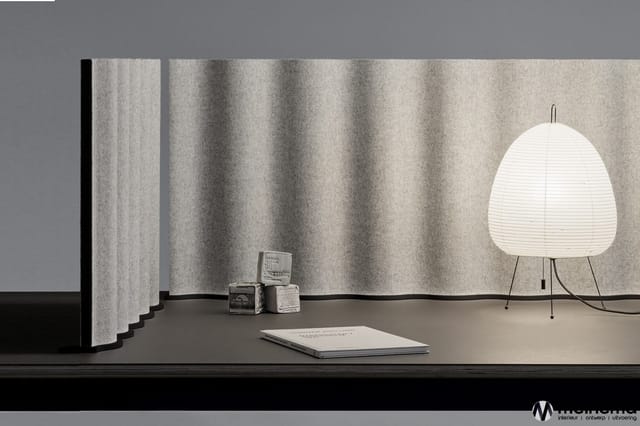 Minimalistische kantooropstelling met grijze gepleisterde wand, zwarte werkblad, witte bollamp op tripod, notitieblok en deco