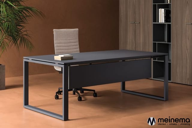 Moderne zwart bureau met grijze frame en zwart onderstel in kantoor met beige stoel, houten kast en plant.