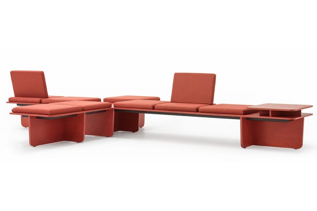 Modulair zitlandschap in terracotta-rood met kussens, hoekbanken en bijzettafels in een open opstelling.