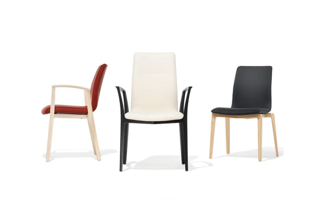 Drie moderne stoelen in verschillende uitvoeringen: rode stoel met armleuningen, crèmekleurige stoel met zwarte poten en zwar