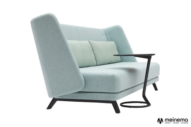 Moderne fauteuil met lichtblauwe bekleding, zwarte poten en armleuningen, decoratief kussen in het midden.