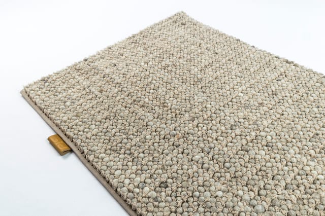 Beige tapijttegel met bolletjestextuurtje en grijze onderlaag, getoond in perspectief.