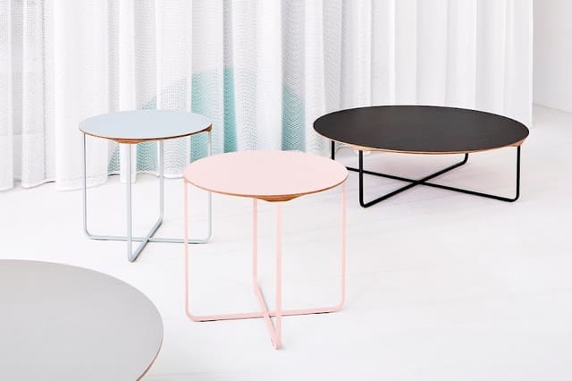Drie ronde bijzettafels in verschillende kleuren: lichtblauw, roze en zwart, met metalen frames in een heldere interieurruimt