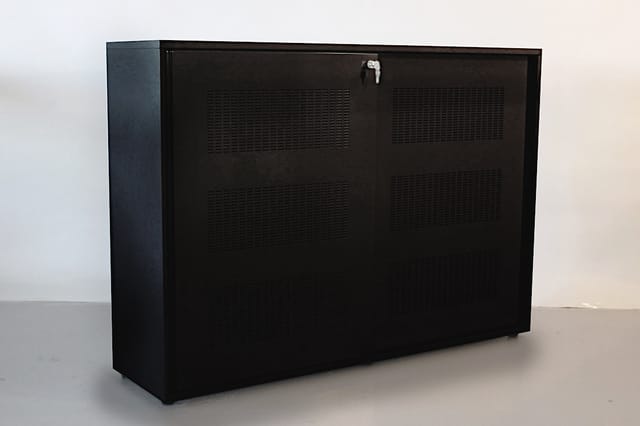 Zwarte kastenwand met metalen framewerk, voorzien van ventilatieopeningen en slot, geplaatst in een lichte ruimte.