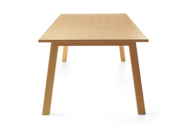 Houten vergadertafel met trapeziumvormig blad en vier rechte poten in licht eikenhout.
