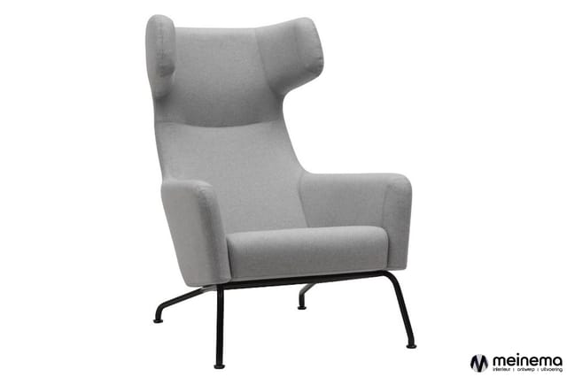 Grijze fauteuil met hoge rug, oorfauteuil-achtige vorm en zwart metalen pootframe tegen witte achtergrond.