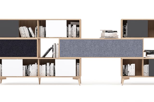 Modulair kastensysteem in natuurlijk hout met grijze en donkerblauwe stofafwerkingen, open vakken met boeken en witte deuren.