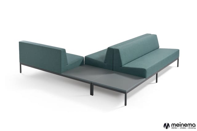 Modulaire bank in grijsgroene stof met zwarte metalen poten, twee delen onder hoek opgesteld rond grijze tafel.