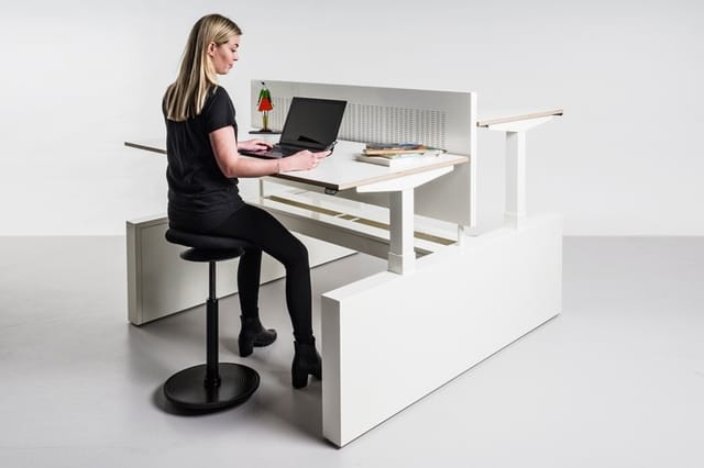 Vrouw aan witte bureau met laptop, zwarte bureaistoel, organizer en decoraties. Moderne kantoorinrichting.
