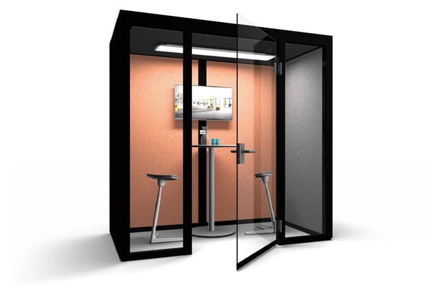 Akoestische belcel met zwart frame, oranje akoestische wandbekleding, twee zithoogtabourets, staanwerkplek, monitor en overhe