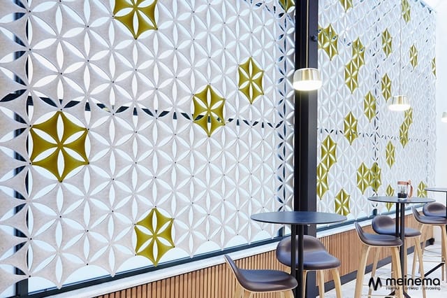 Moderne kantoorruimte met geometrische wandpanelen in wit, goud en navy, zwarte hanglamp, houten vloer en minimalistisch inge