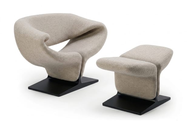 Beige loungestoel met organische vorm op zwart platform en bijpassende beige voetenbankje op zwart platform.