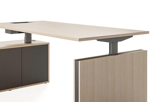 Elektrisch verstelbaar bureau met lichte houten blad en grijze stalen poot, gecombineerd met licht houten kastfront.