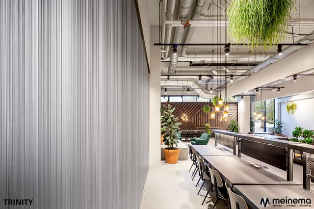 Modern kantoorinterieur met lange werkoppervlakken, zwarte stoelen, hangende planten, houten wandaccenten en industrieel plaf