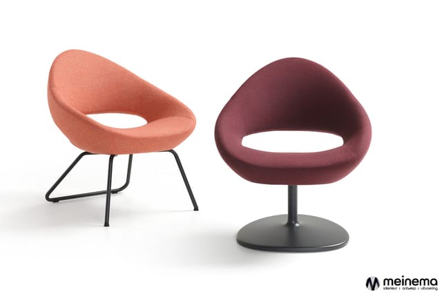 Twee moderne loungefauteuils: links koraalrood model op zwart metalen poten, rechts bordeauxrood model op zwart voetje.