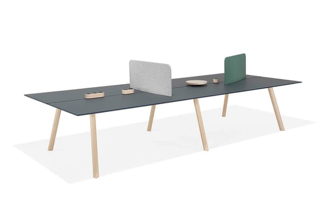 Lange vergadertafel met donkergrijs blad en houten poten, met grijze akoestische schermen en groene bureauscherm op het tafel